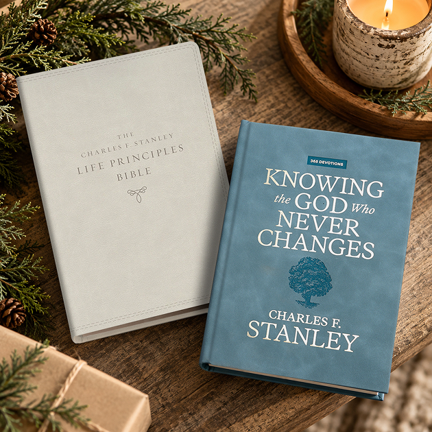 The Charles Stanley Life Principles Bible and the devotional Knowing the God Who Never Changes, with greenery and a candle.
