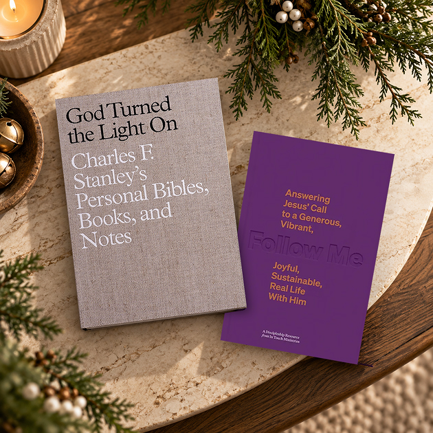 God Turned the Light On: Charles F. Stanley’s Personal Bibles, Books, and Notes, beside the purple book Follow Me, with Christmas greenery and a candle.