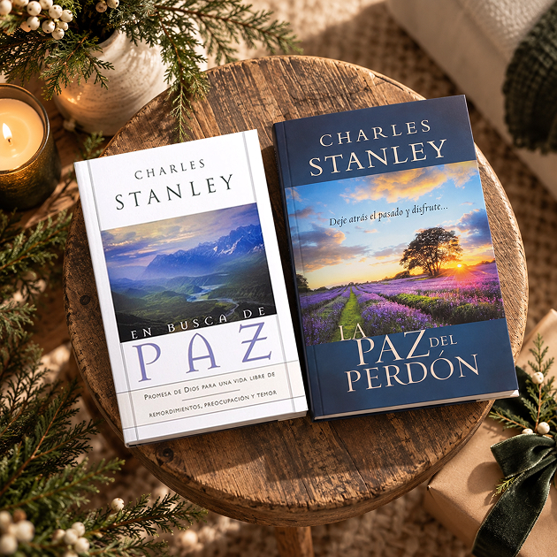 Los libros En busca de paz y La paz del perdón, de Charles Stanley, sobre un banco de madera con adornos navideños.
