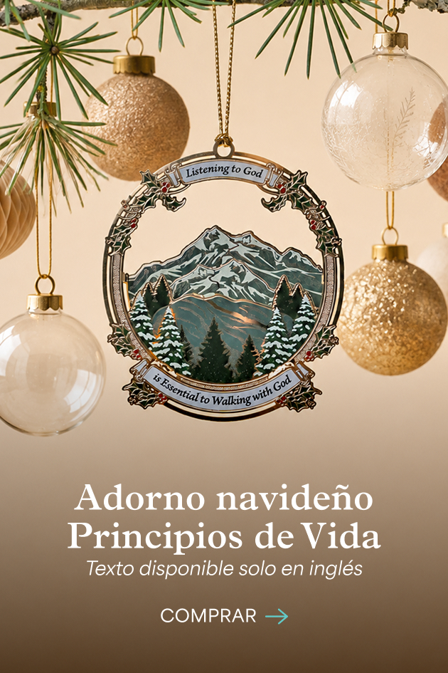 Un adorno navideño Principios de Vida con una montaña nevada y pinos, colgado entre esferas de vidrio y doradas. Adorno navideño Principios de Vida. Texto disponible solo en inglés. Comprar.