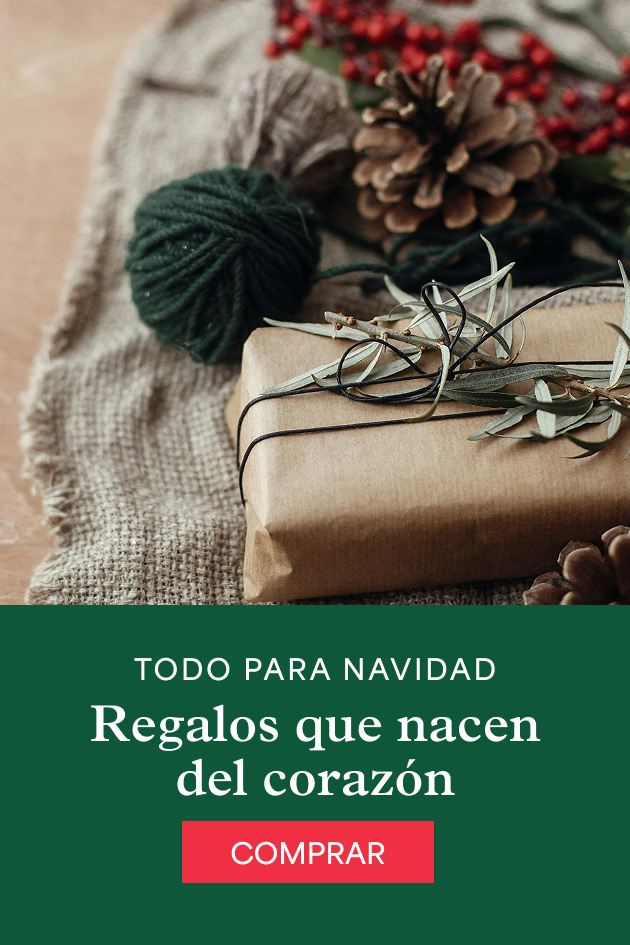 Un regalo envuelto en papel kraft con cordel, junto a una piña y bayas rojas sobre tela de yute. Todo para Navidad. Regalos que nacen del corazón.