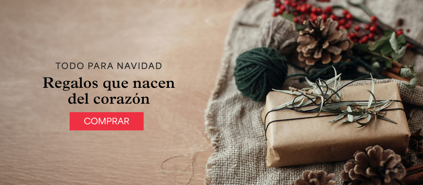 Un regalo envuelto en papel kraft con cordel, junto a una piña y bayas rojas sobre tela de yute. Todo para Navidad. Regalos que nacen del corazón.